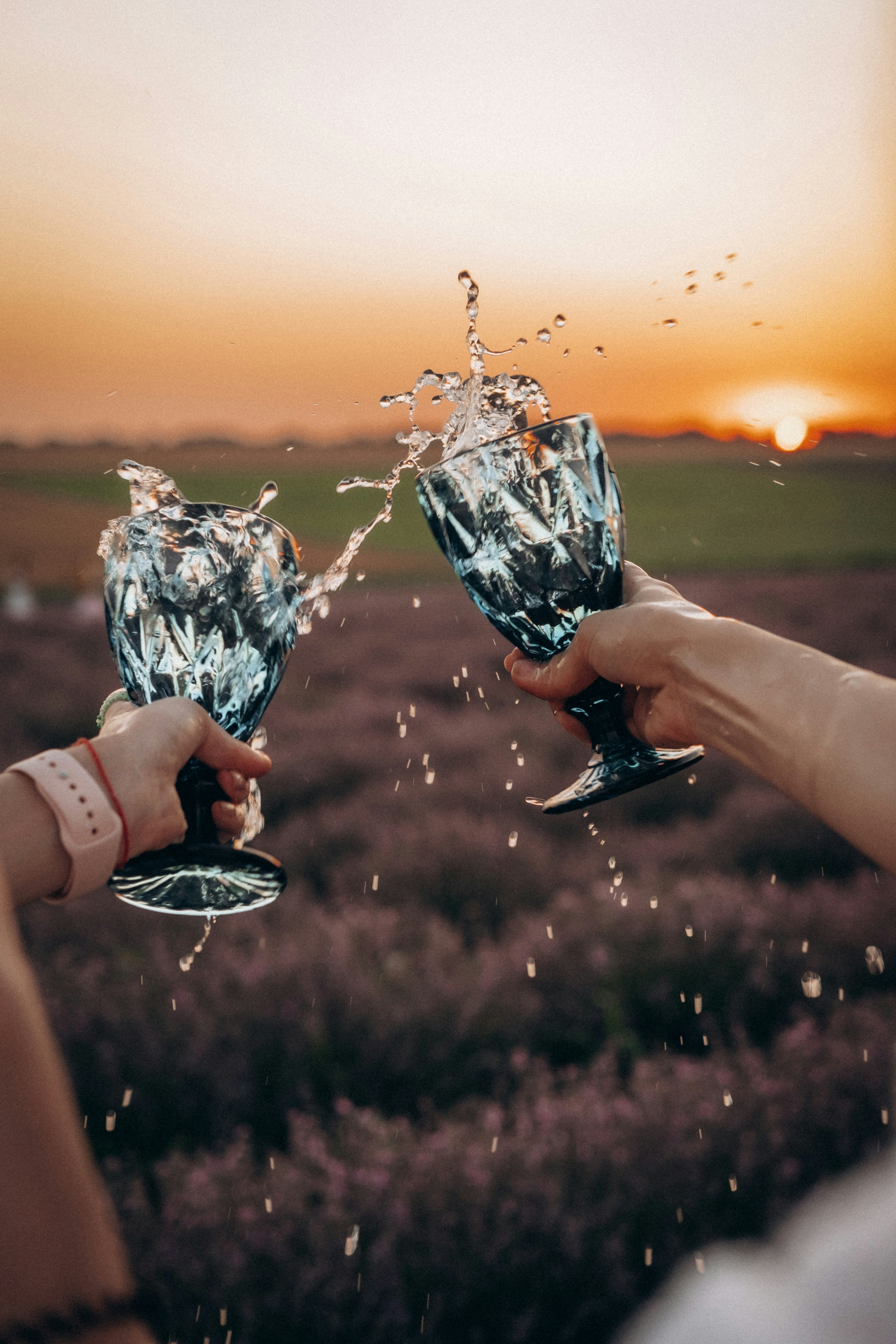 person holding clear glass cup with water during sunset